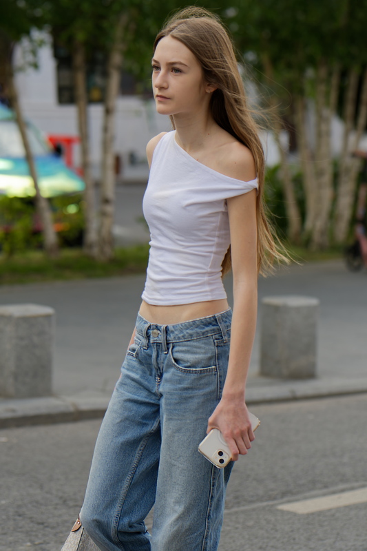 Girl wearing a white Fashion Nova Eva effortless one shoulder top and blue jeans
